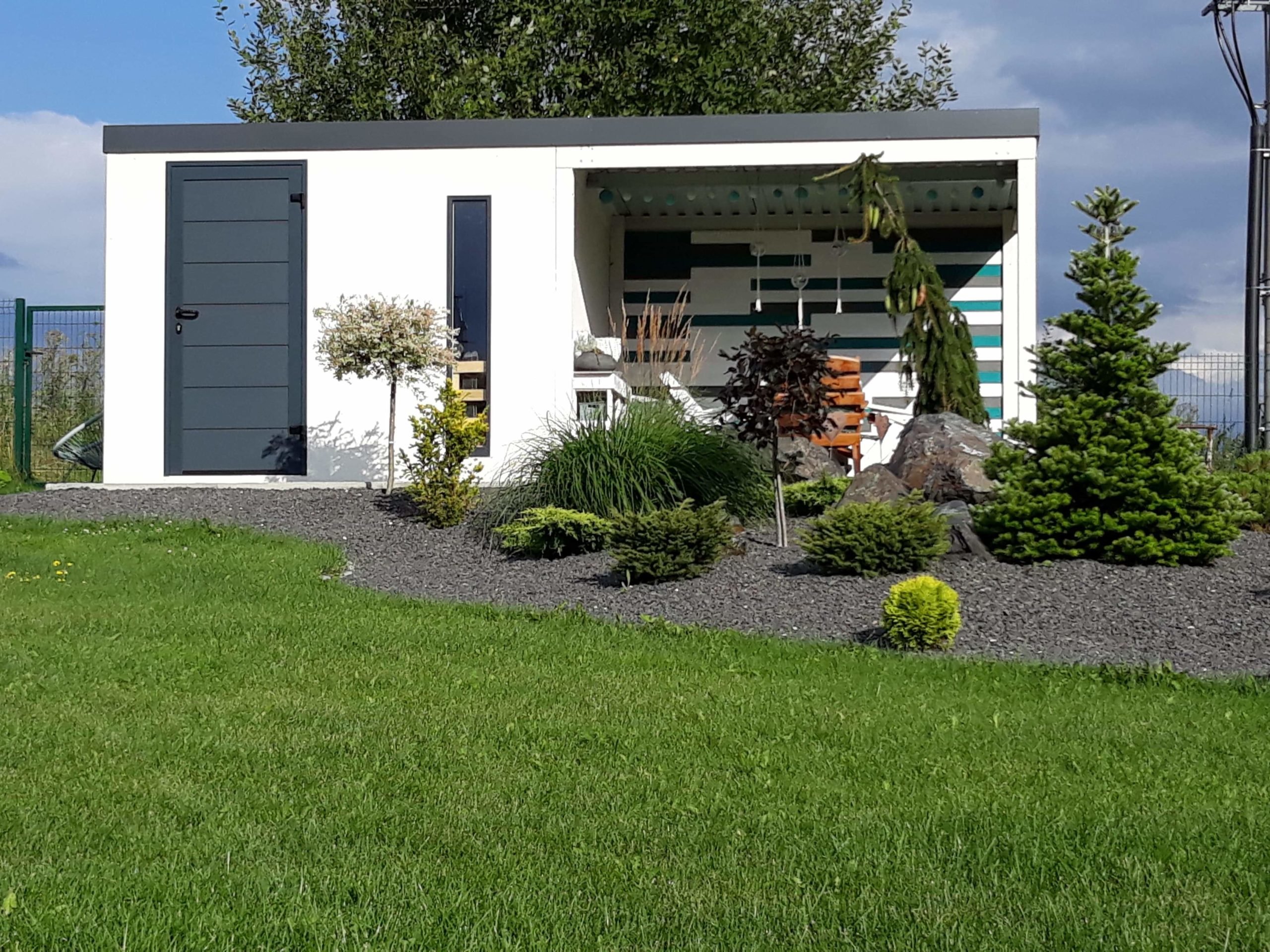 Predná časť bieleho domčeka s prestrešením za záhradkou