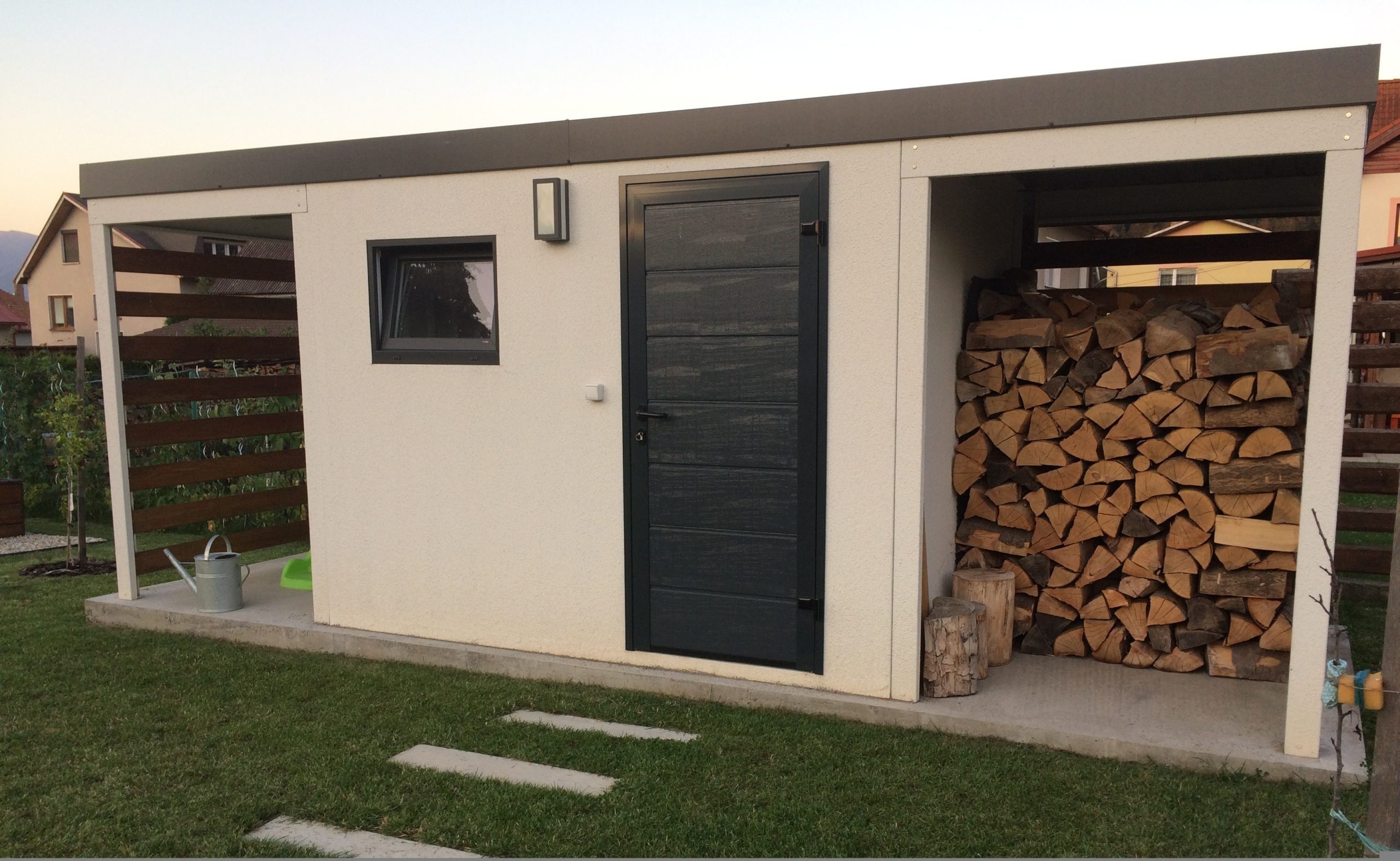 Biely záhradný domček s drevom pod pravým prestrešením