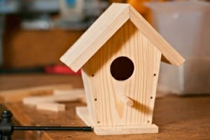 Dřevěná budka pro ptáčky na stole.