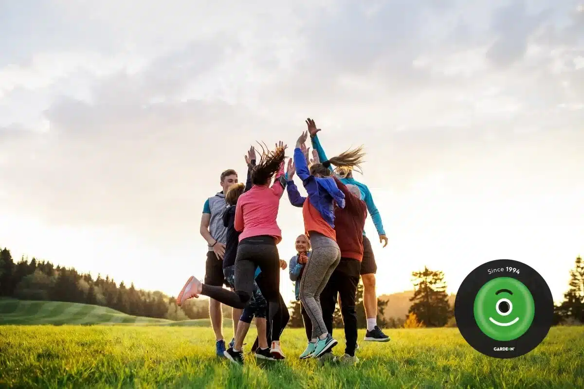 Skupina aktivních přátel radostně skáče po společné sportovní aktivitě v přírodě.