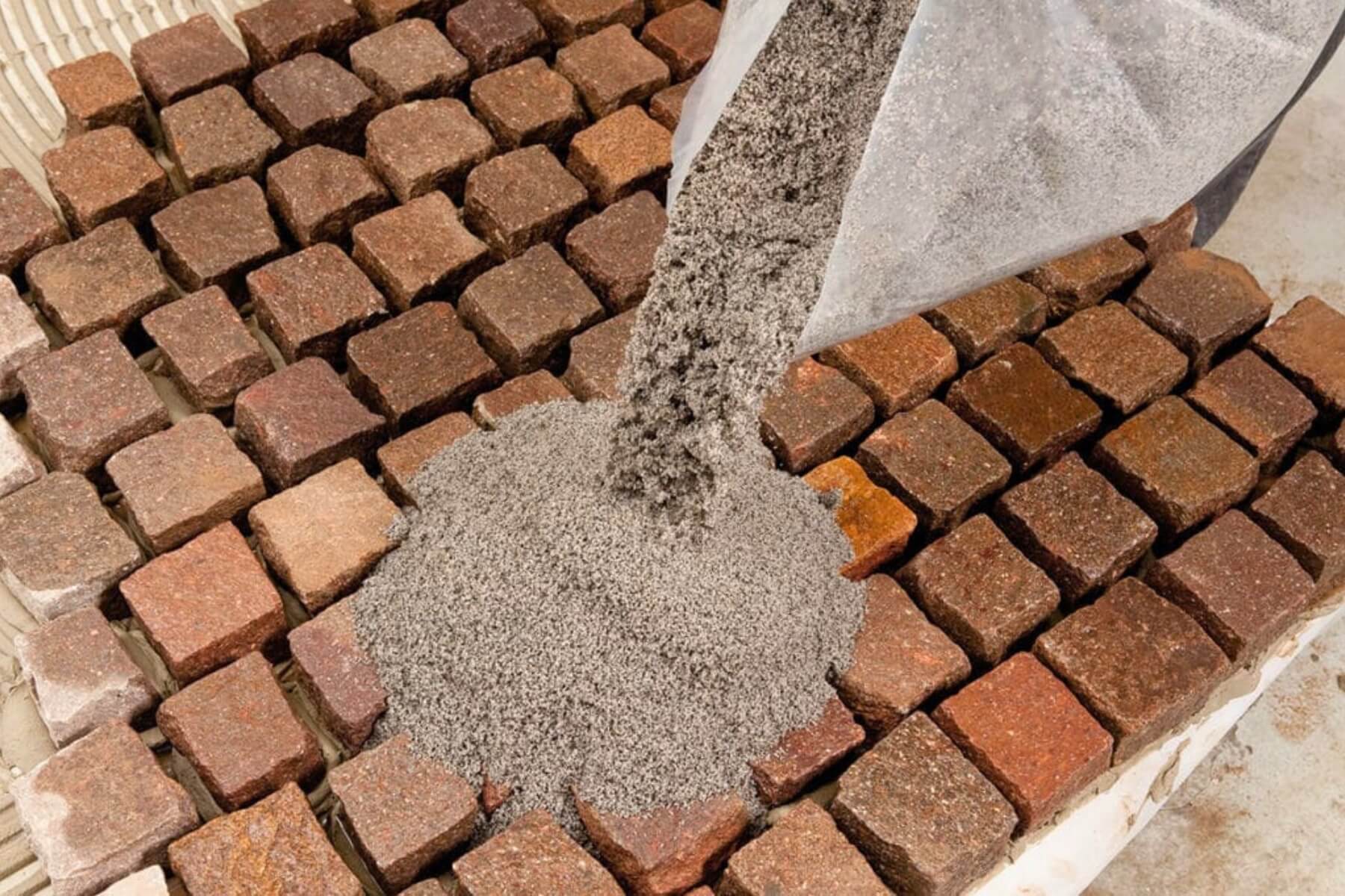 Sypání polymerového písku na zámkovou dlažbu.