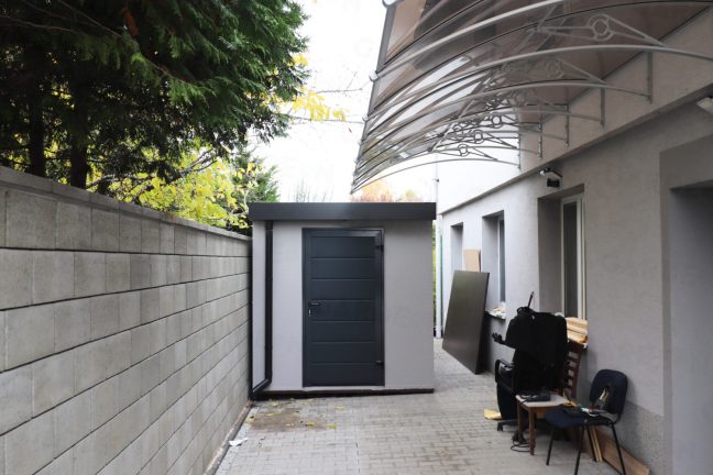 Záhradný domček v svetlosivej omietke pri rodinnom dome