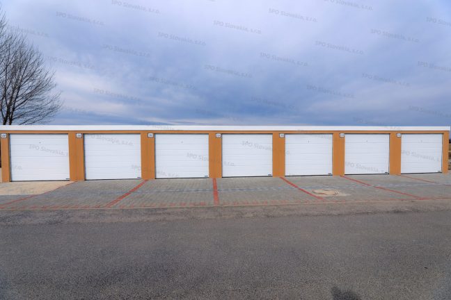 Montované radové garáže v kukuricovej omietke s bielymi garážovými bránami Hormann