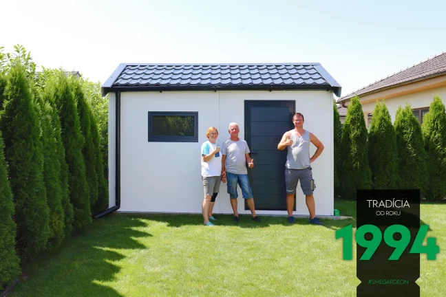 Montážník se zákazníky před zahradním domkem se špičatou střechou