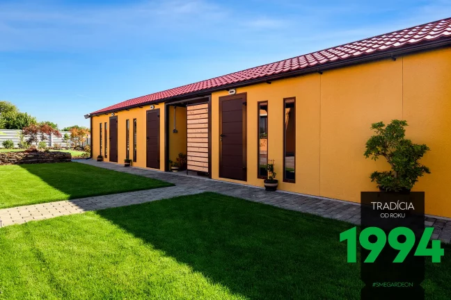 Atypická montovaná garáž ve žluté omítce s hnědými doplňky.