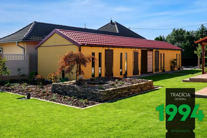 Atypická montovaná garáž ve žluté omítce s hnědými doplňky a sedlovou střechou.