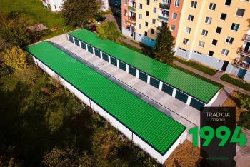 Řadové garáže v bílé omítce se zelenou střechou