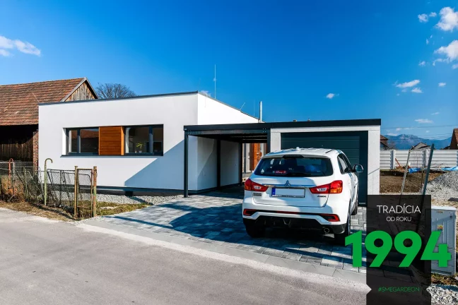 Bílé auto před garáží s přístřeškem u domu