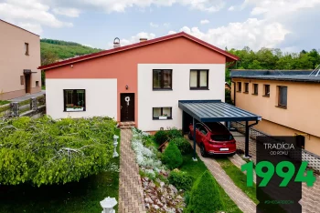 Červené auto pod přístřeškem u domu