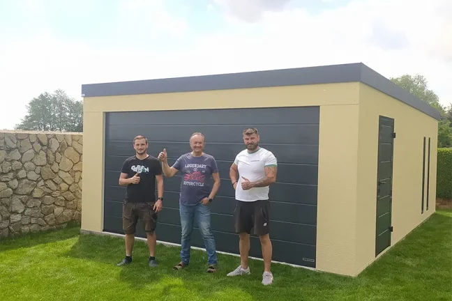 Montážníci se zákazníkem před žlutou garáží na zahradě