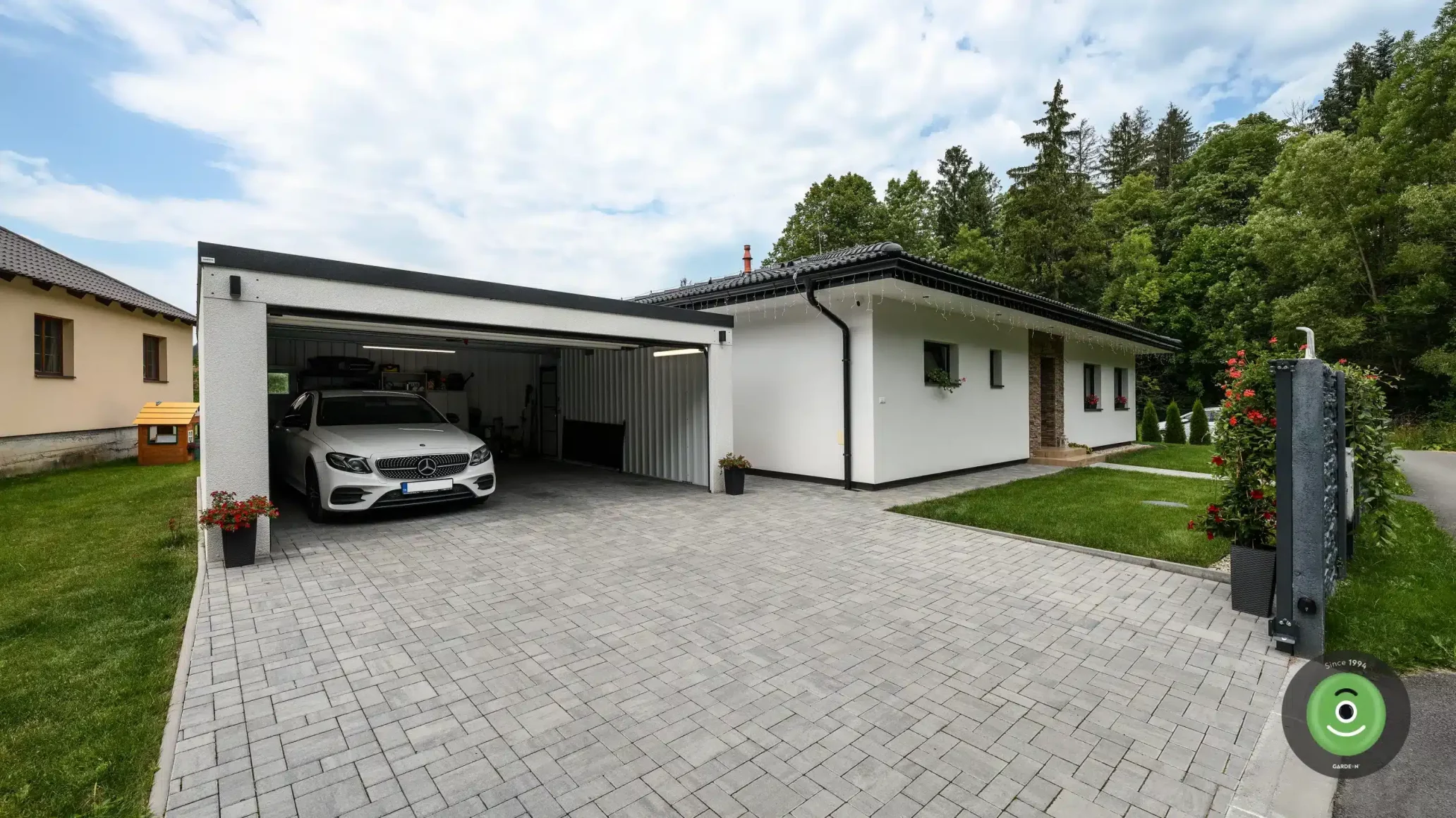 Bílá GARDEON garáž s pultovou střechou na zámkové dlažbě