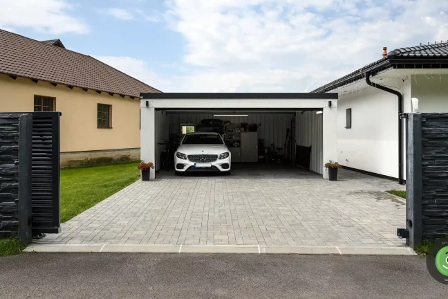 Garáž s pultovou střechou u bílého rodinného domu