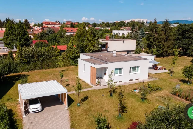 Přístřešek pro dvě auta s bílou střechou vedle bílého domu.