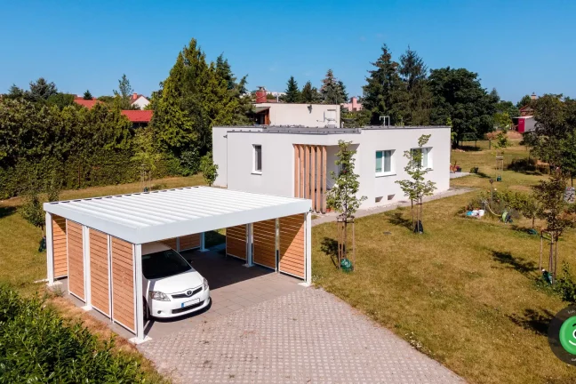 Přístřešek pro dvě auta s bílou střechou mezi ovocnými stromky