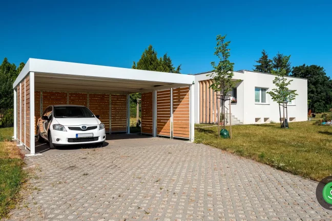 Přístřešek GARDEON s bílou střechou u bílého rodinného domu.