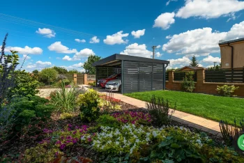 Přístřešek s černou střechou a černou výplní u zahrady