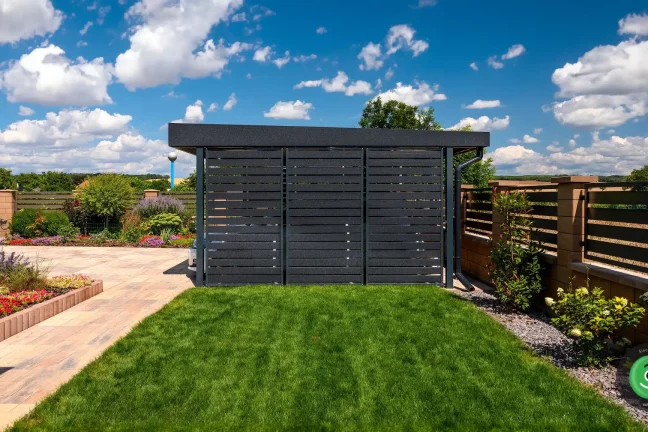 Černá kovová výplň na přístřešku v zahradě s barevnými kvítky