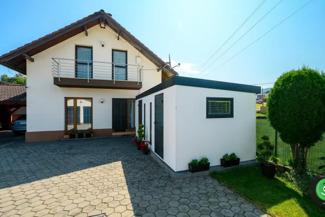 Zahradní domek s bílými stěnami u zahrady s domem