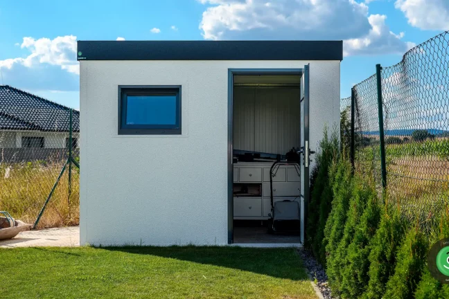 Malý bílý zahradní domek s černou atikou