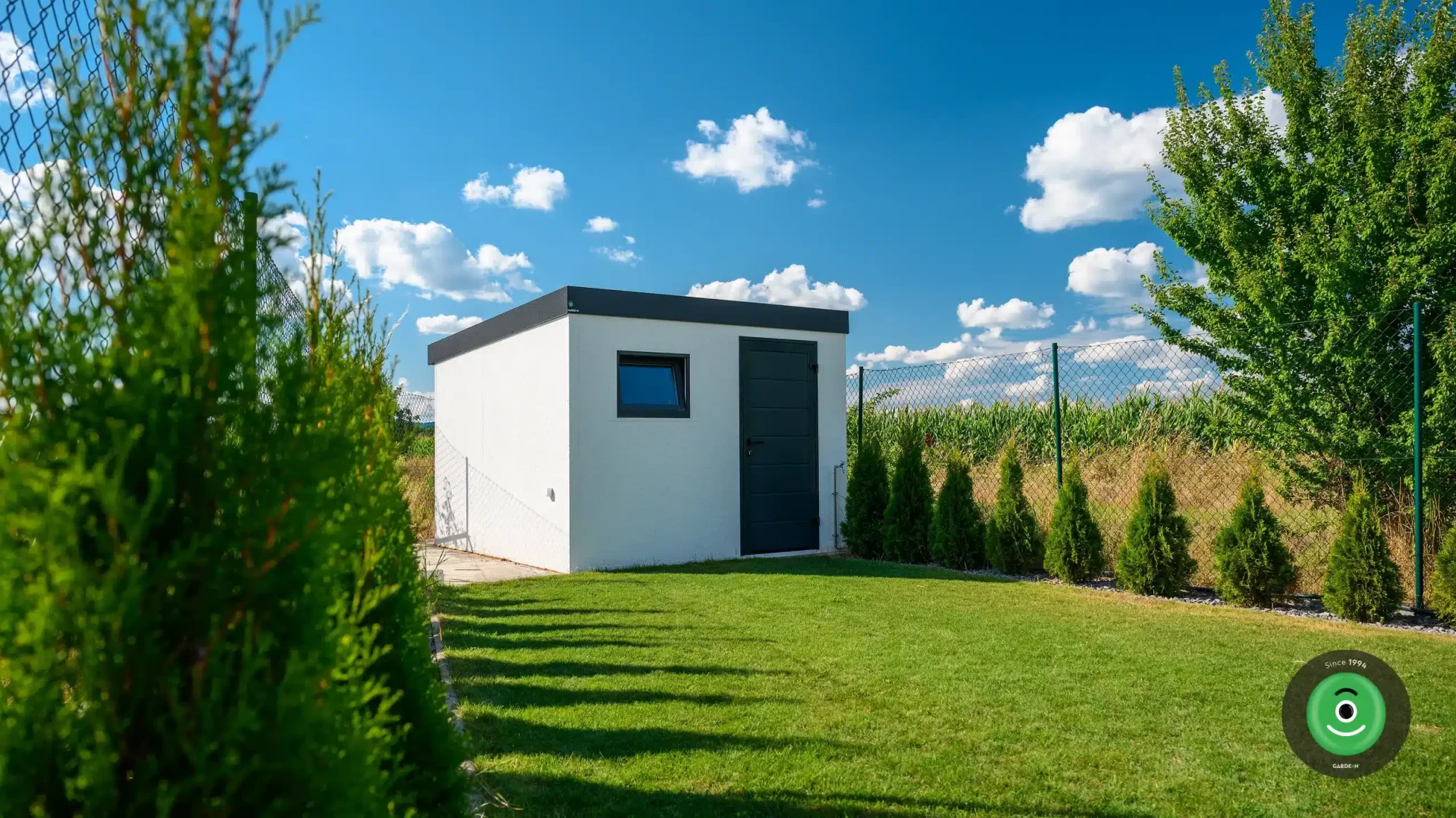 Bílý GARDEON zahradní domek obklopený stromky