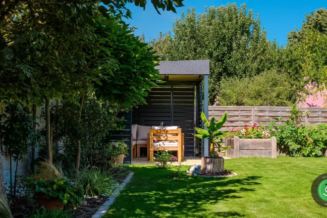 Gardeon pergola s posezením obklopená stromy a květinami