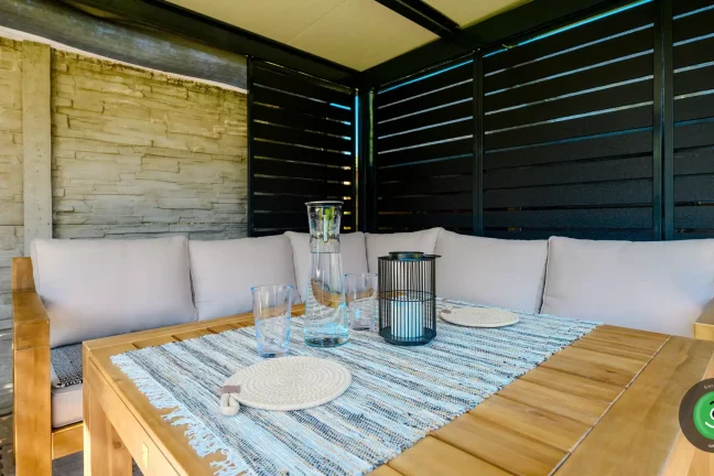 Detail na dřevěný stůl s posezením pod Gardeon pergolou