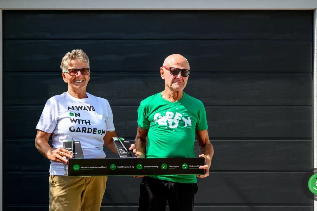 Spokojení zákazníci před garáží, kteří drží závěsný systém GARDEON