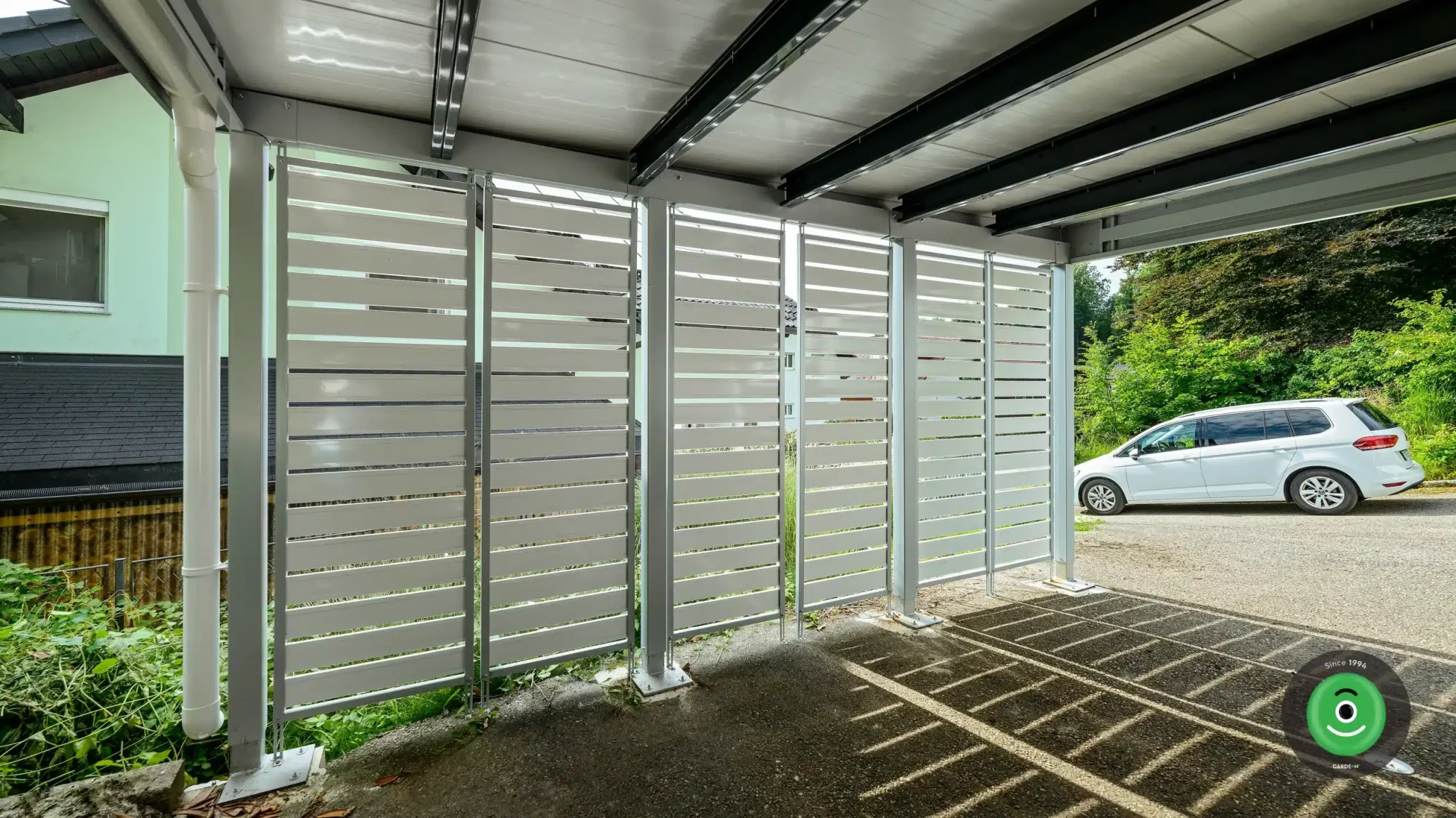 Detail na bílou kovovou výplň přístřešku pro dvě auta