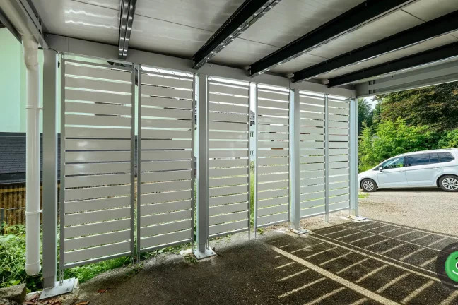 Detail na bílou kovovou výplň přístřešku pro dvě auta