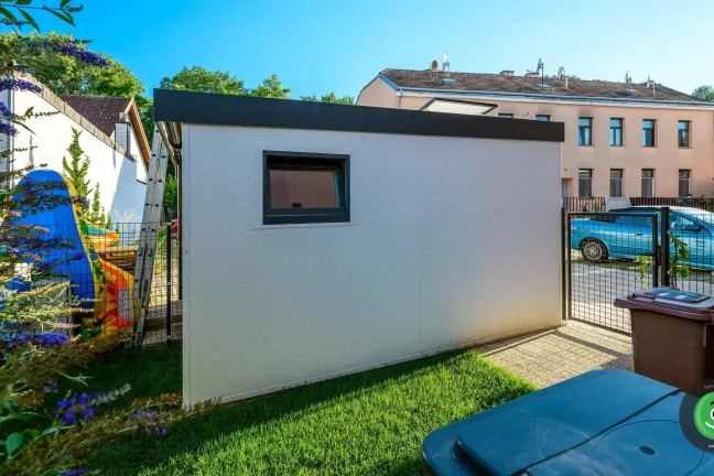 Boční strana zahradního domku s bílou omítkou