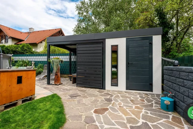 Černý přístřešek se zahradním domkem s bílou omítkou