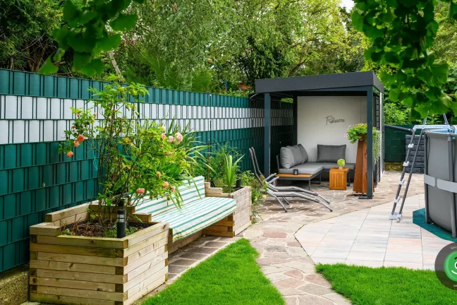 Přístřešek GARDEON vedle záhonů s květinami