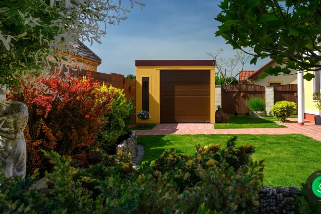 Garáž se žlutou omítkou v krásném zeleném prostředí