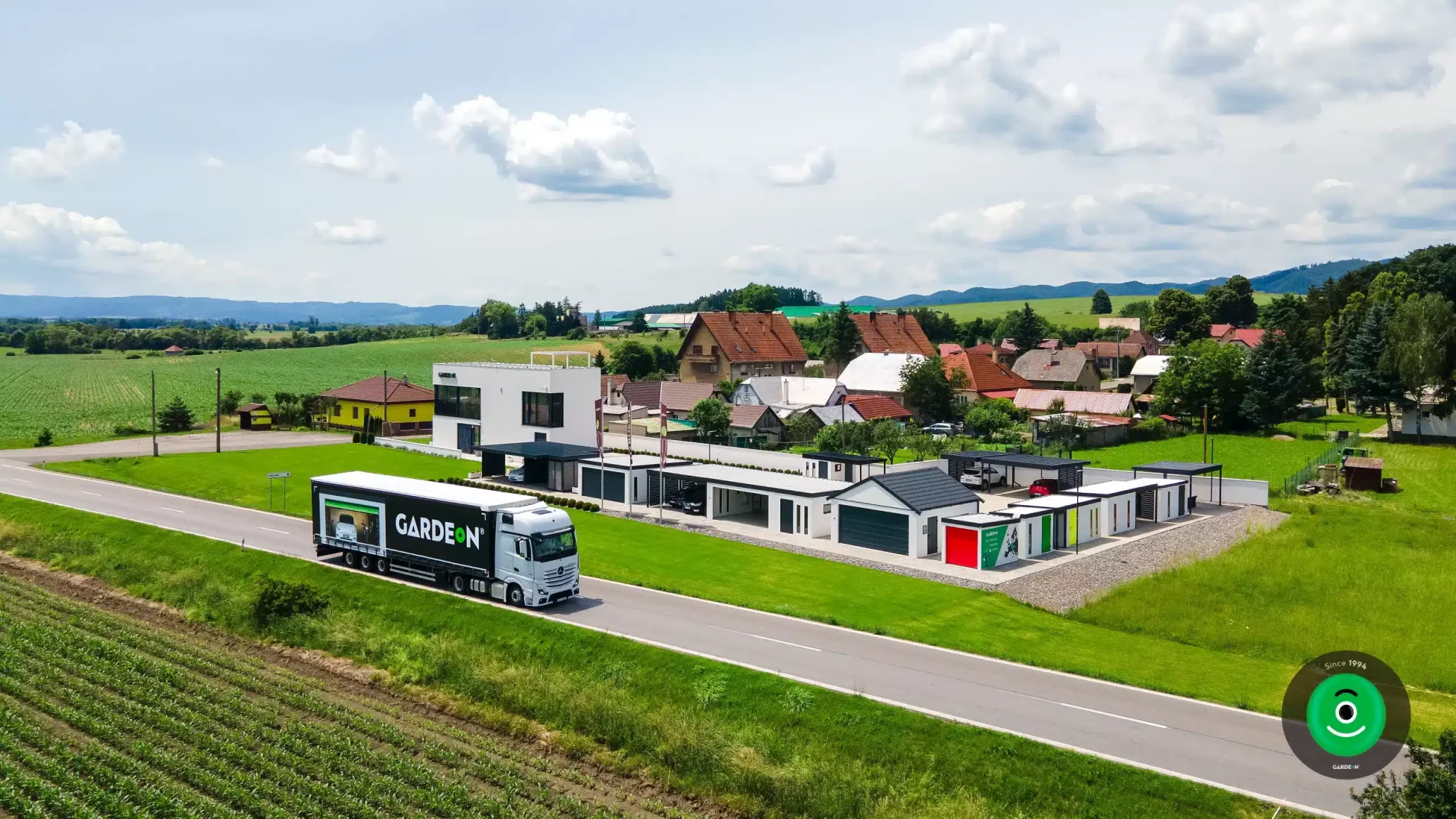 Kamion na cestě s nápisem GARDEON a zobrazenou fotografií garáže