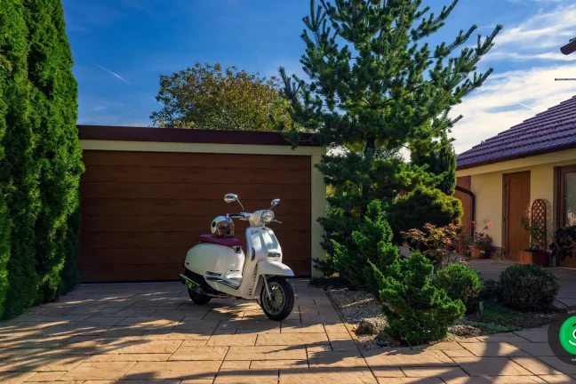 skútr u garáže se širokou branou