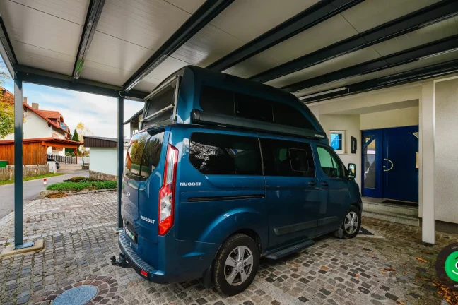 auto pod přístřeškem před vchodovými dveřmi