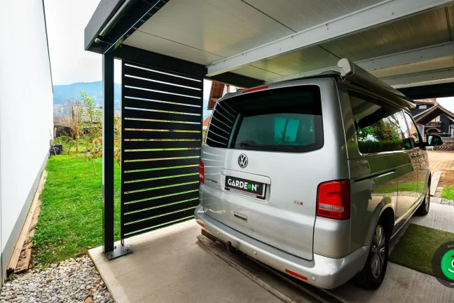 auto pod přístřeškem s černou kovovou výplní