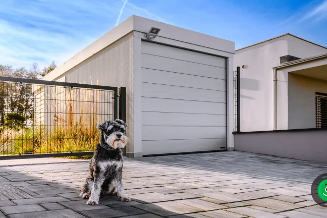 malý pejsek před garáží s nainstalovaným světlem pod atikou