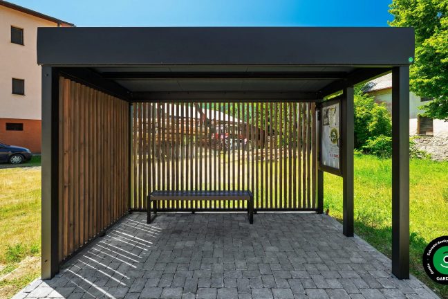 Zastávkový přístřešek z kovové konstrukce.