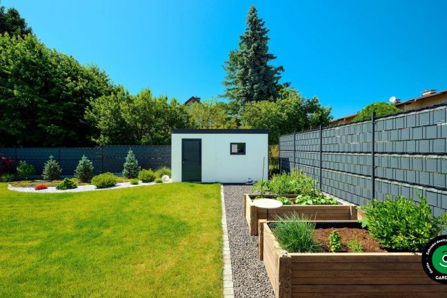 Světlý zahradní domek pod korunami stromů.