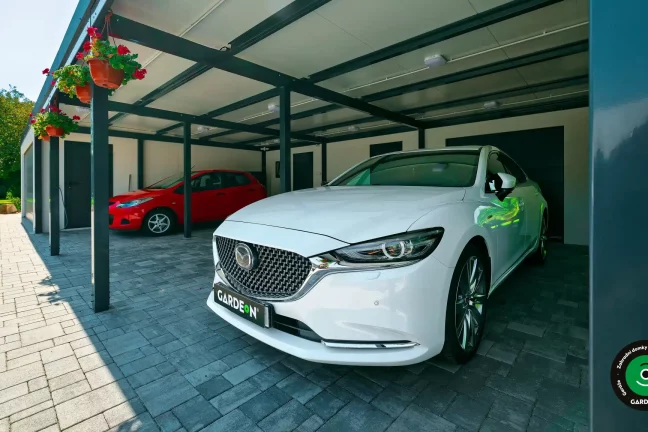 Atypická stavba garáže s dvojitou bránou a velkým přístřeškem.