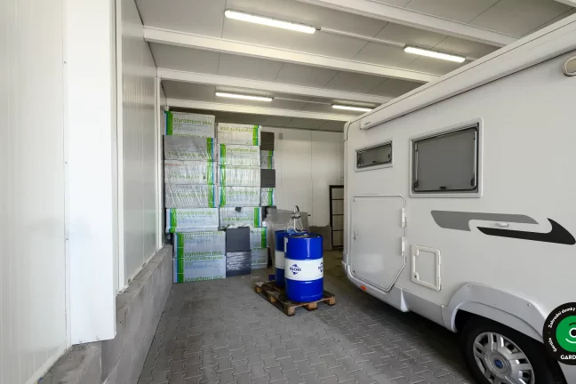 Vnitřek garáže s parkovaným autem a uskladněným nářadím.