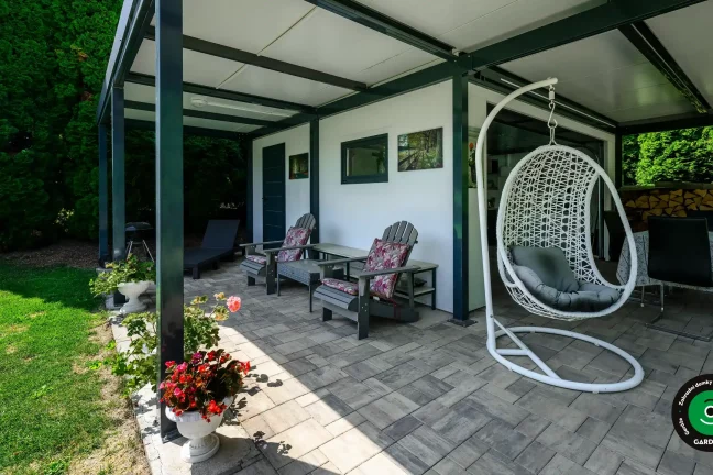 Zahradní domek s přístřeškem poskytujícím stín pro letní posezení.