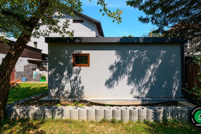 Boční pohled na garáž s oknem a zahradou.