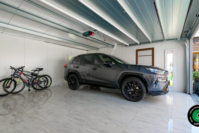 Prostorný interiér garáže s autem a koly.