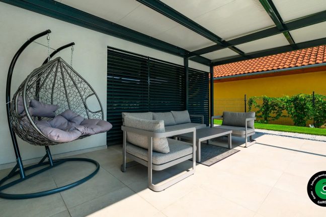 Zastřešené sezení s houpacím křeslem a pohovkou.