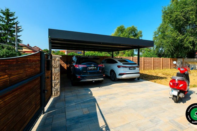 Moderní přístřešek pro dvě auta s tmavou střechou a vydlážděným dvorem.