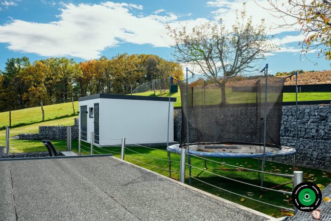 Boční pohled na garáž s trampolínou a gabionovou zdí
