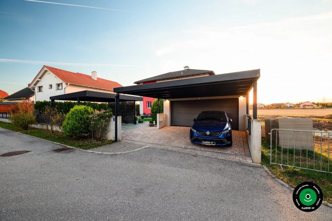 Moderní garáž s přístřeškem u domu s upravenou předzahrádkou a keři