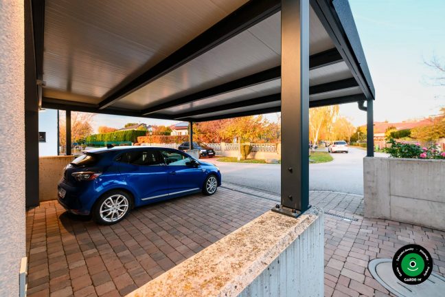 Auto zaparkované pod přístřeškem s výhledem na ulici